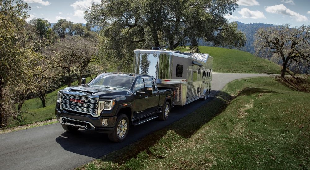Black 2021 GMC Sierra 2500 HD towing a camper.
