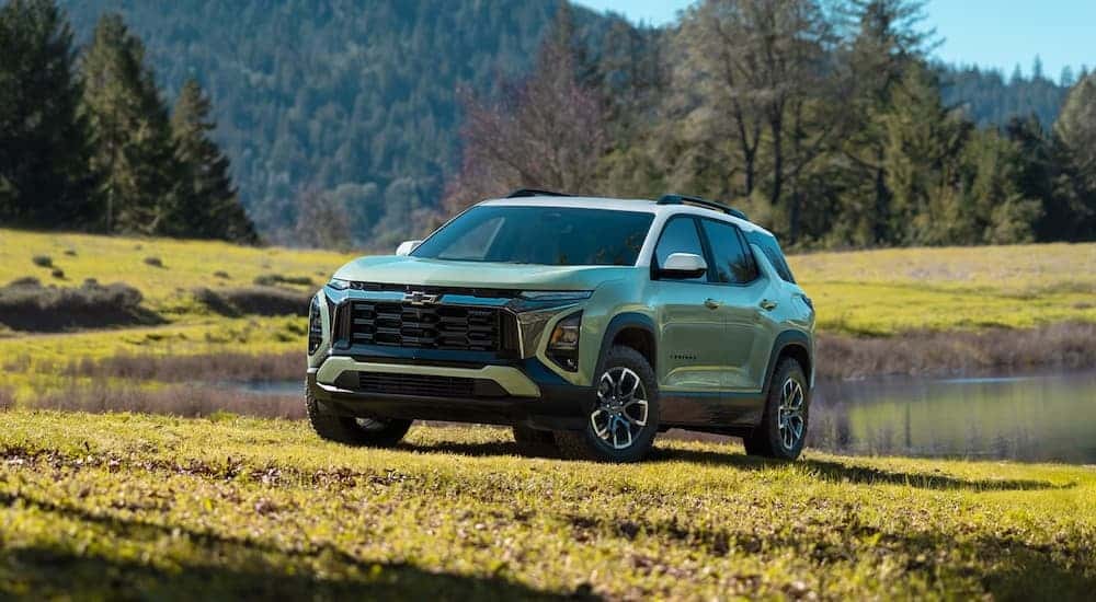 Green 2026 Chevy Equinox parked on grass near a pond