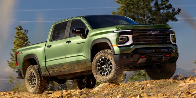 Green 2027 Chevy Silverado 1500 crew cab on a rocky mountain trail