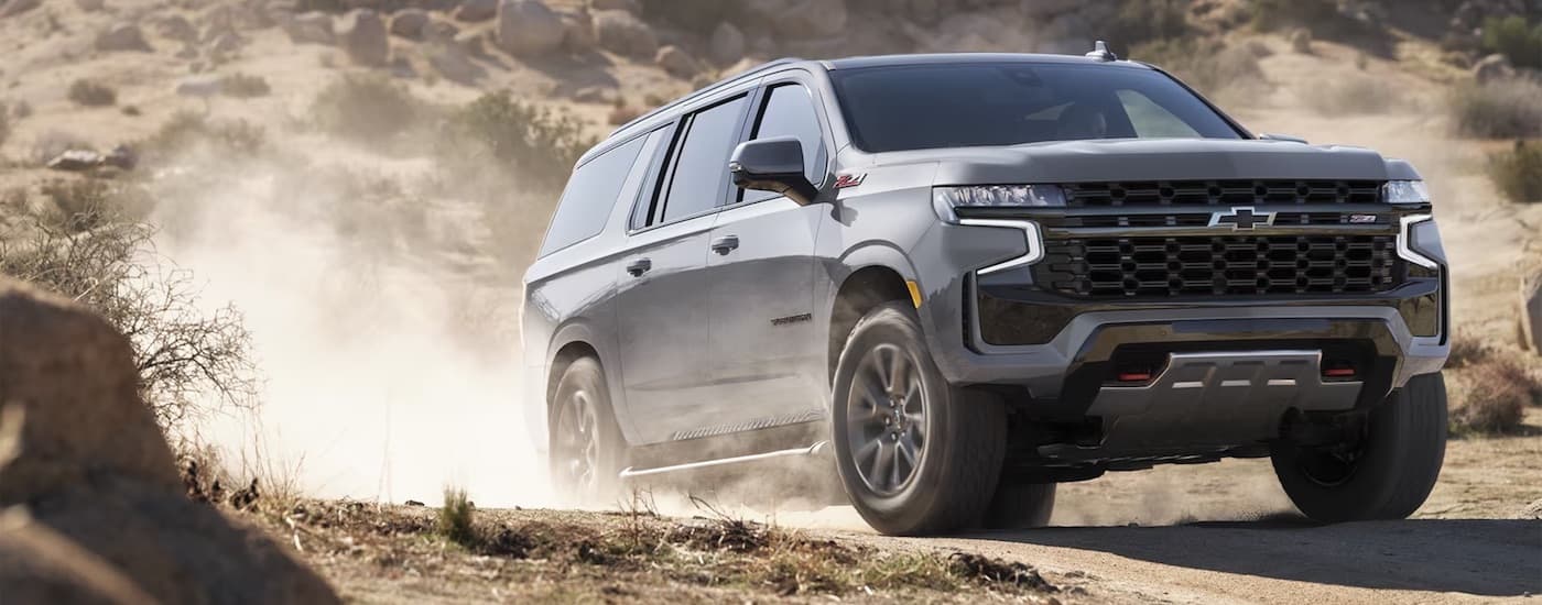 A grey 2024 Chevy Suburban Z71 driving off-road from a Chevrolet dealer near Olathe.