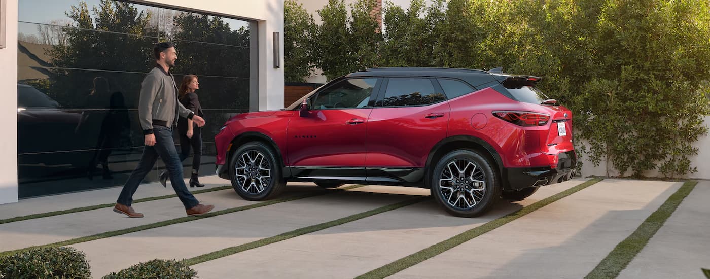 A red 2025 Chevy Blazer RS is parked in front of a garage door.