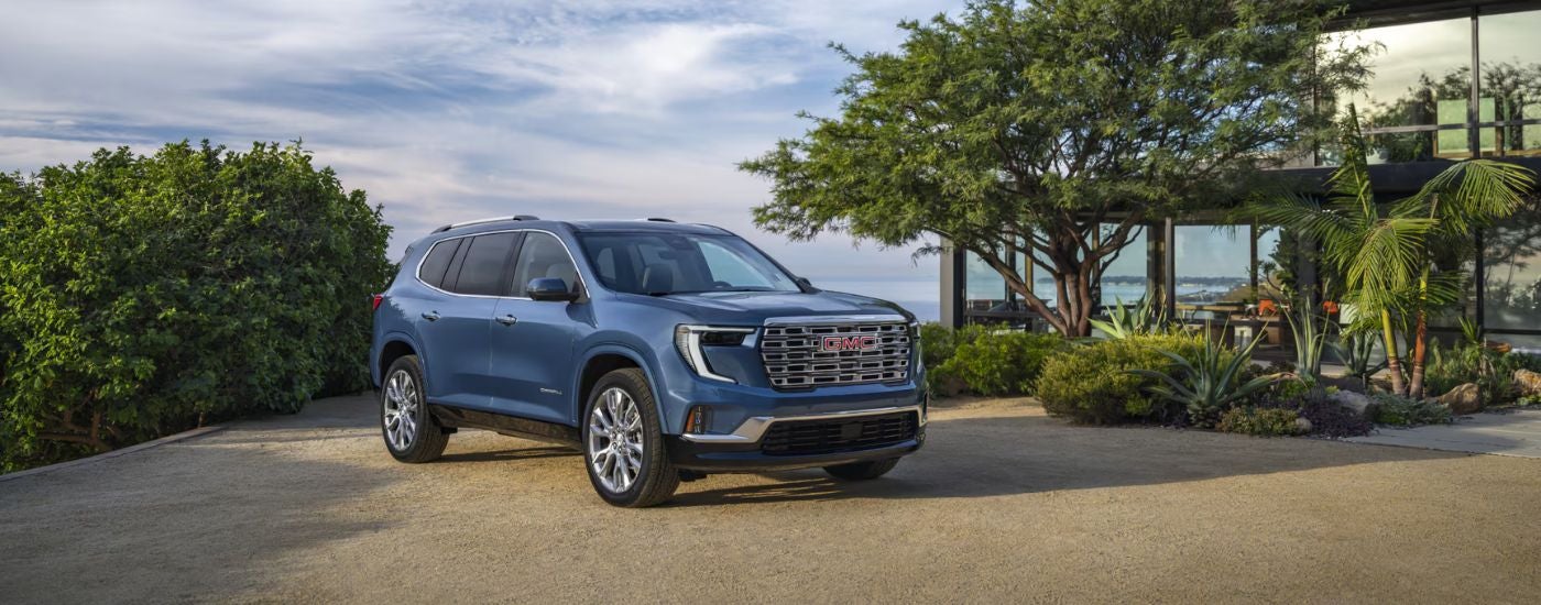 A blue 2025 GMC Acadia Denali parked near a GMC dealer.