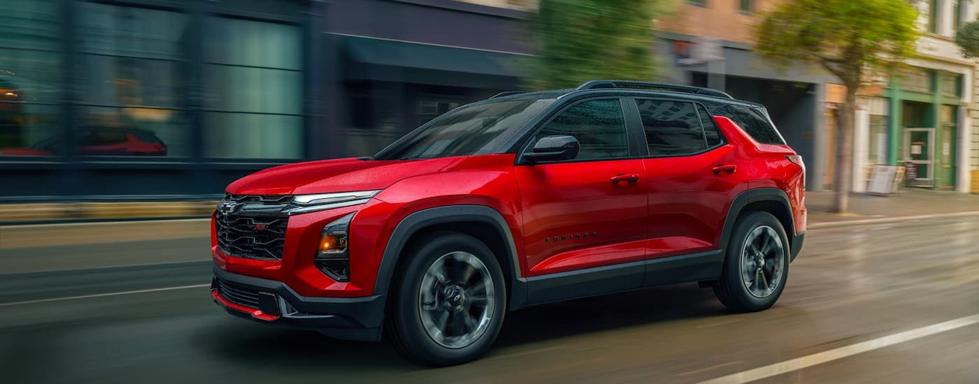Red 2026 Chevy Equinox driving down a city street.