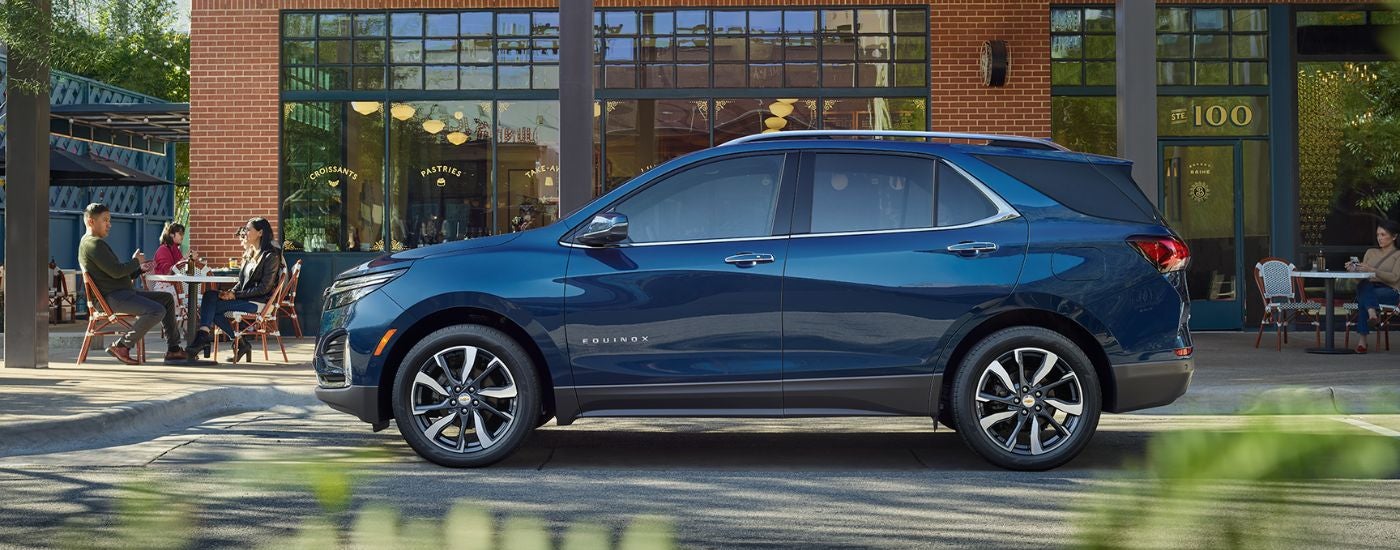 A side angle view of a blue 2022 Chevy Equinox parked by a curb.