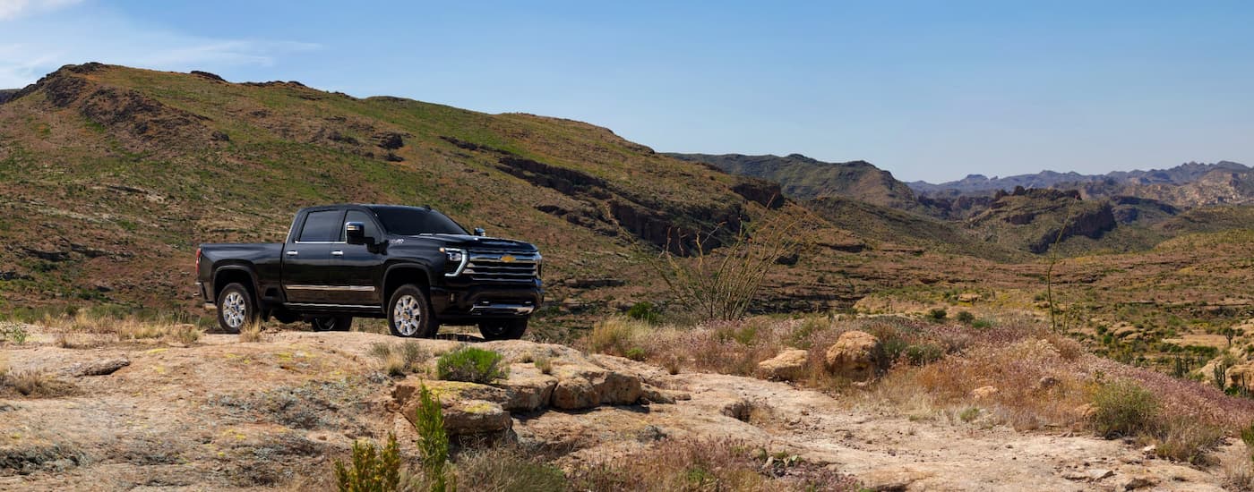 A black 2025 Chevy Silverado 2500 HD parked off-road on a hill.