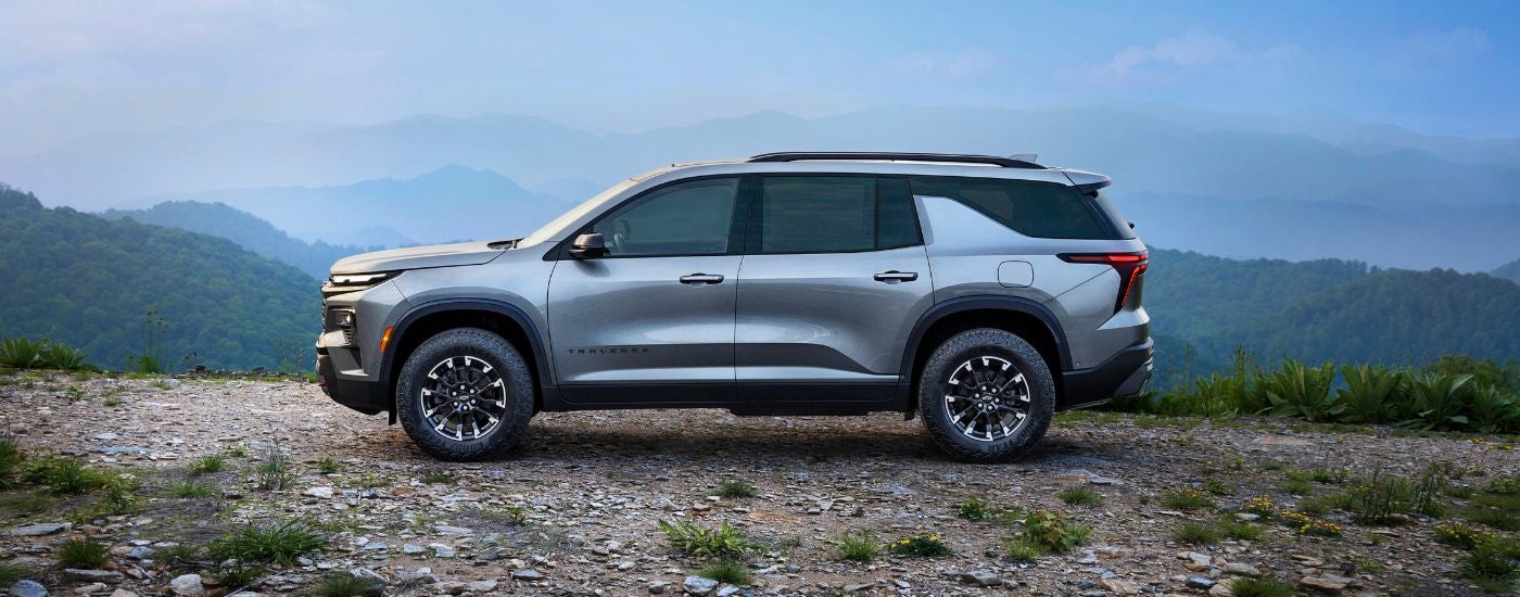 Side angle view of a silver 2024 Chevy Traverse Z71 parked off-road.