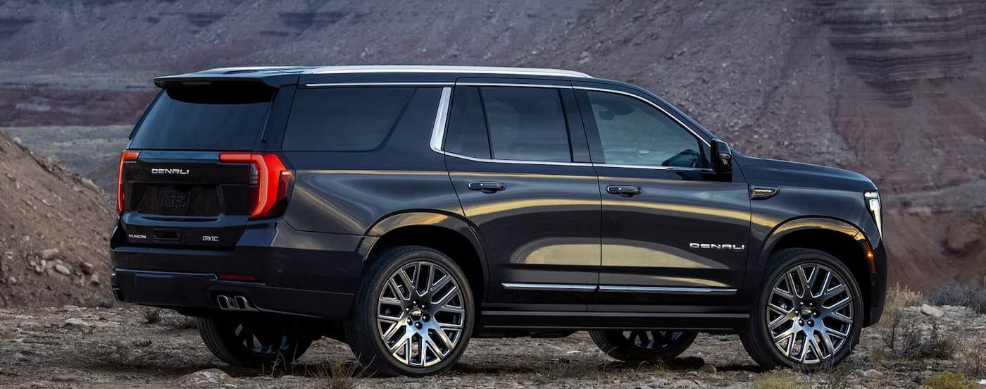 A black 2025 GMC Yukon Denali parked off-road.